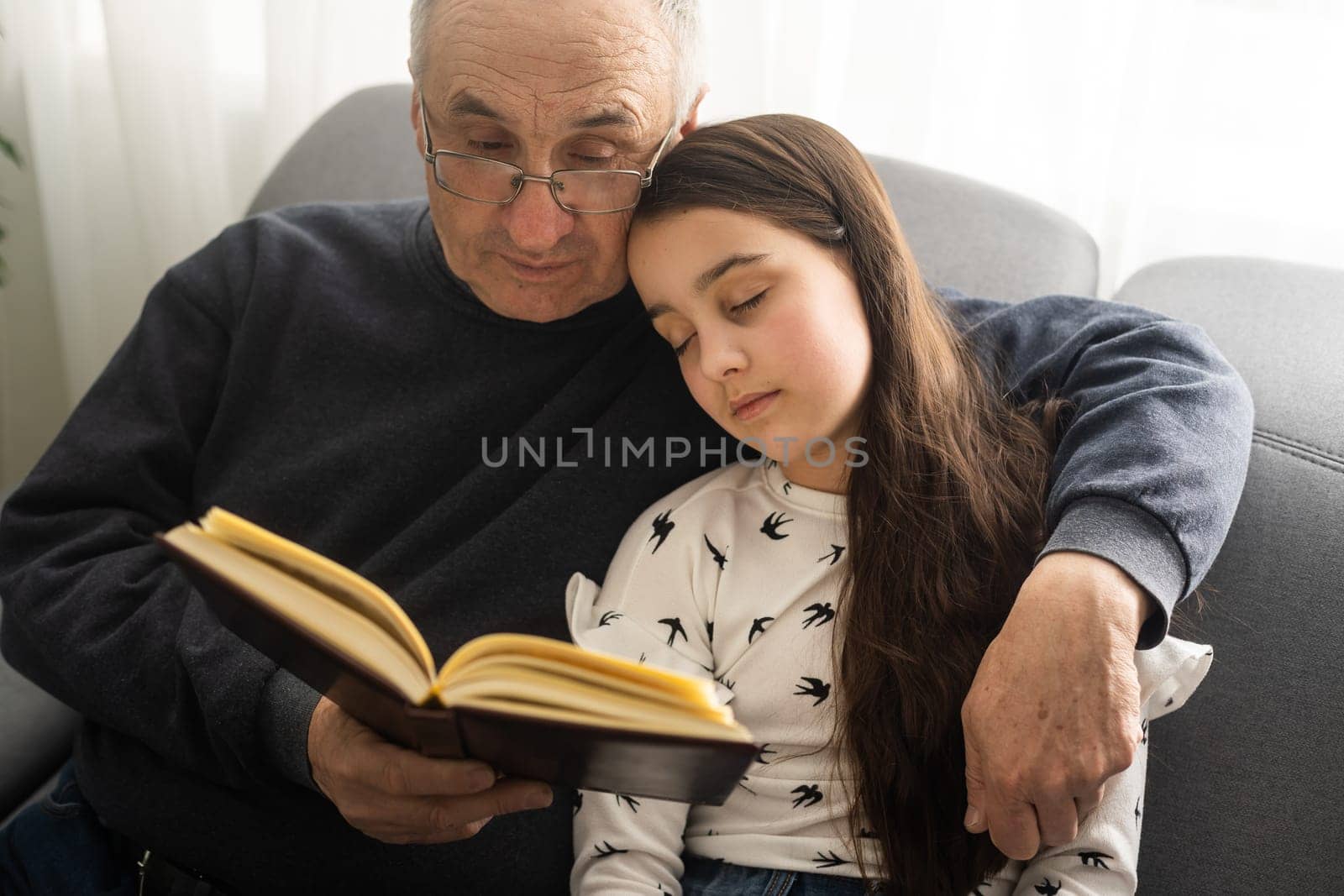 Book, family and children with a girl reading to her grandfather on the floor of their living at home. Kids, read and story with a senior man and granddaughter bonding in their house during a visit