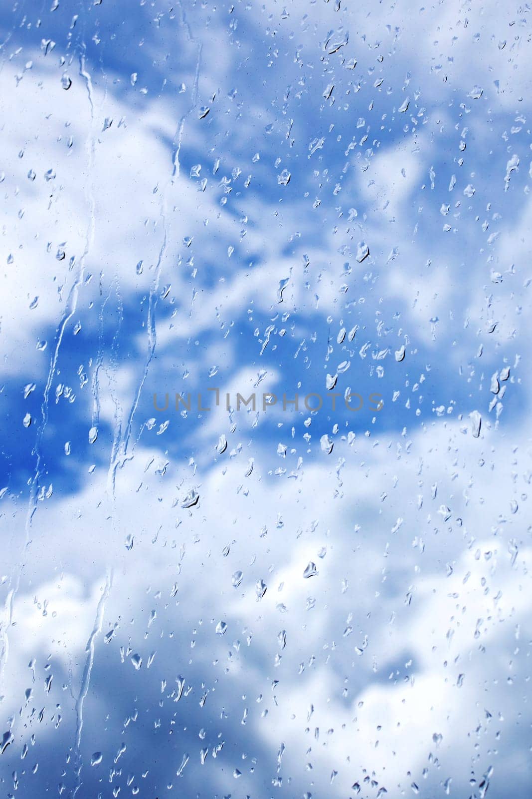 Abstract background of rain drops on glass on a background of blue bright sky