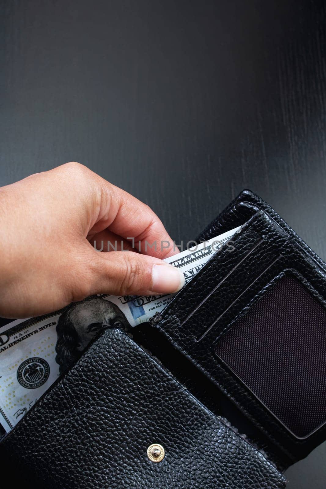 One hundred dollar bill in black wallet in hand, copy space