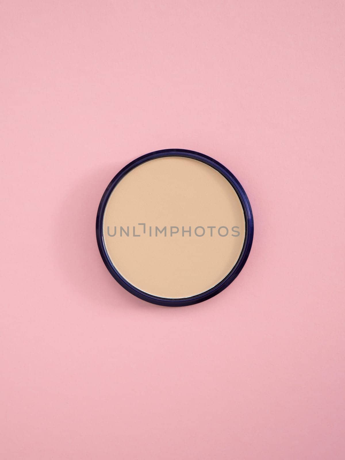 Beige facial concealer powder. Top view of nude face powder in round case on pink paper background. Fashion cosmetic, makeup product. Bronzer and concealer texture for perfect complexion. Copy space by Halina