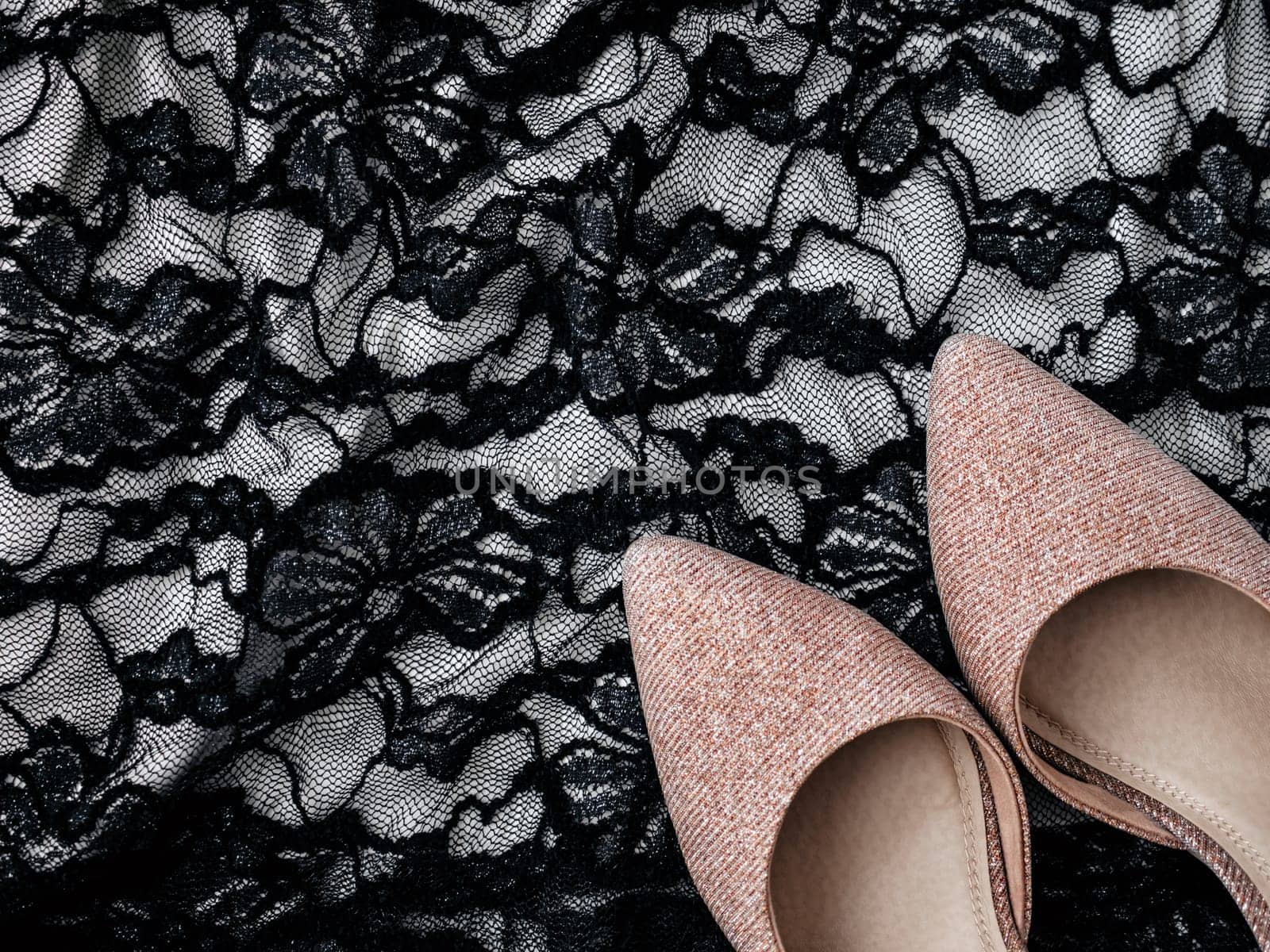 Glittery pink shoes and lace black dress as background. Sexy fashion concept with women's clothes and accessories. Flat lay, top view. Minimal feminine vogue concept. Party time
