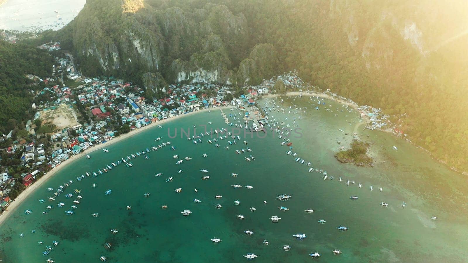 Many boats in the turquoise lagoon at sunset. Seascape with blue bay and boats view from above. El nido, Palawan, Philippines. traditional Filipino wooden outrigger boat called a banca. Summer and travel vacation concept