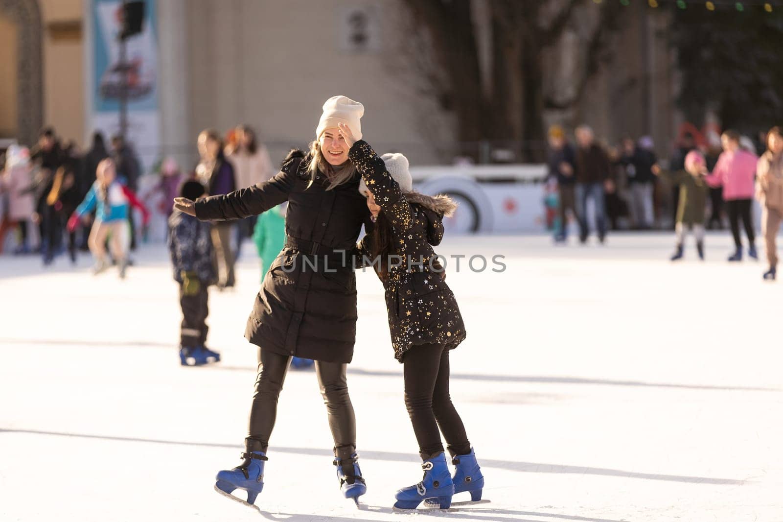 Adorable young mother with her daughter on the ice rink.