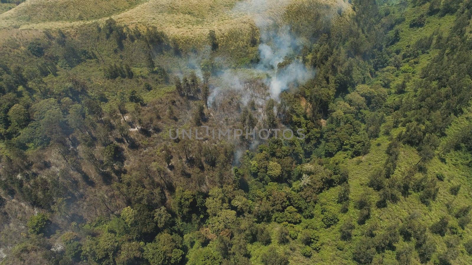 aerial view forest fire smoke on slopes hills. wild fire in tropical forest, Java Indonesia. natural disaster fire in Southeast Asia
