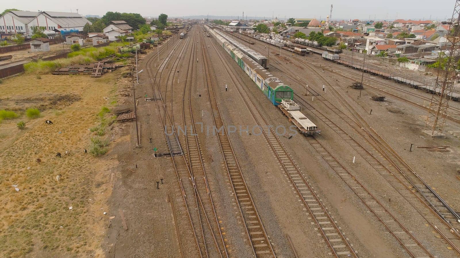 freight train with cisterns and containers on railway station Surabaya Indonesia. Wagons with goods on railroad. Heavy industry. railway station in an asian city among buildings.
