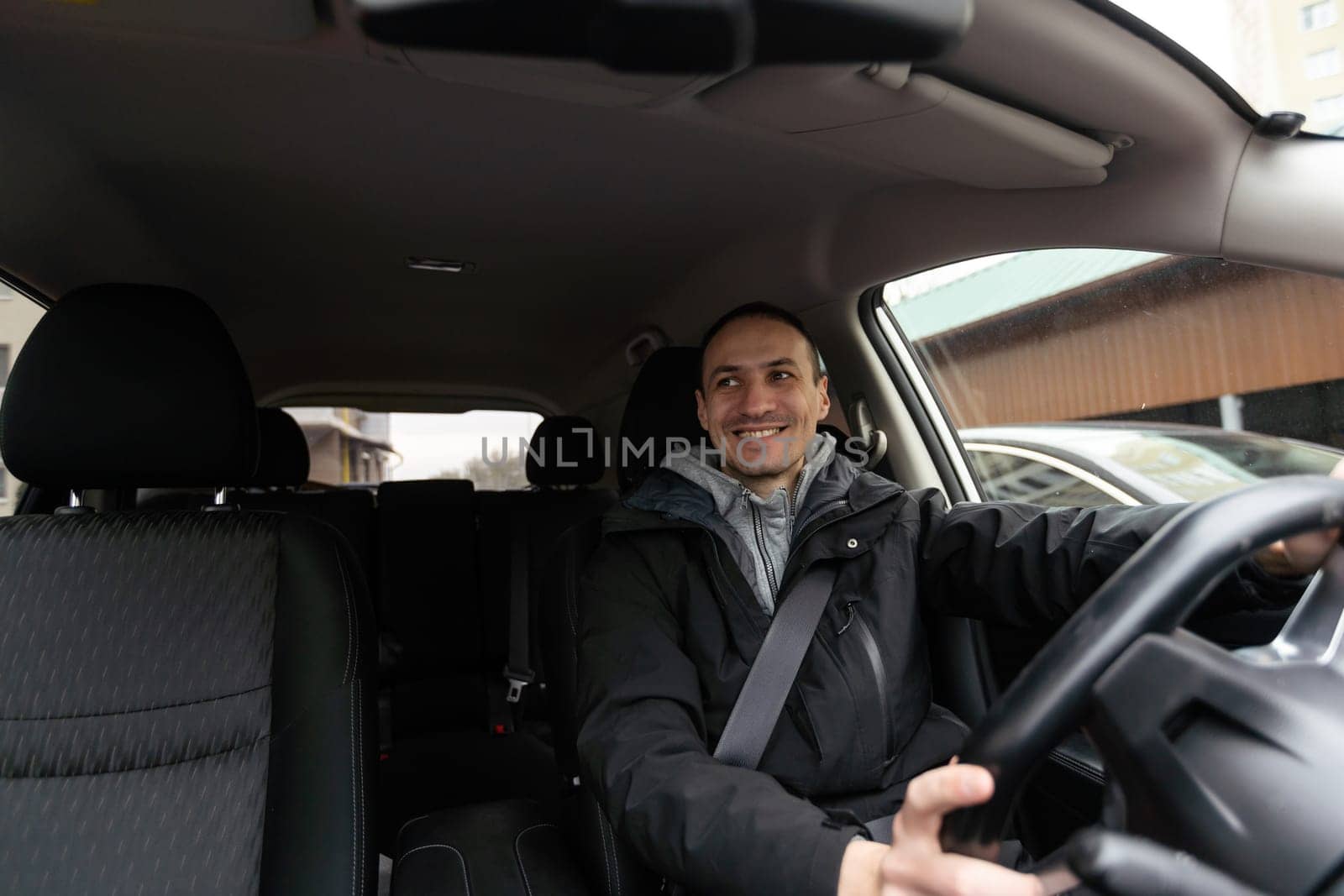 Man of style and status. Handsome young man in full suit smiling while driving a car. High quality photo