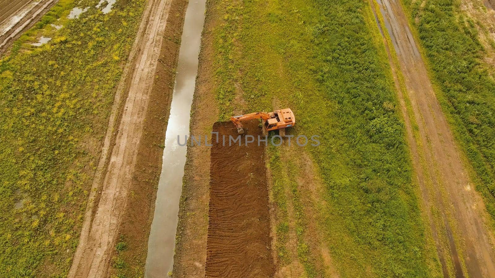 Excavator is digging an irrigation canal. Aerial view:Excavator digging a deep trench.excavator is digging an drainage canal in the agricultural field.