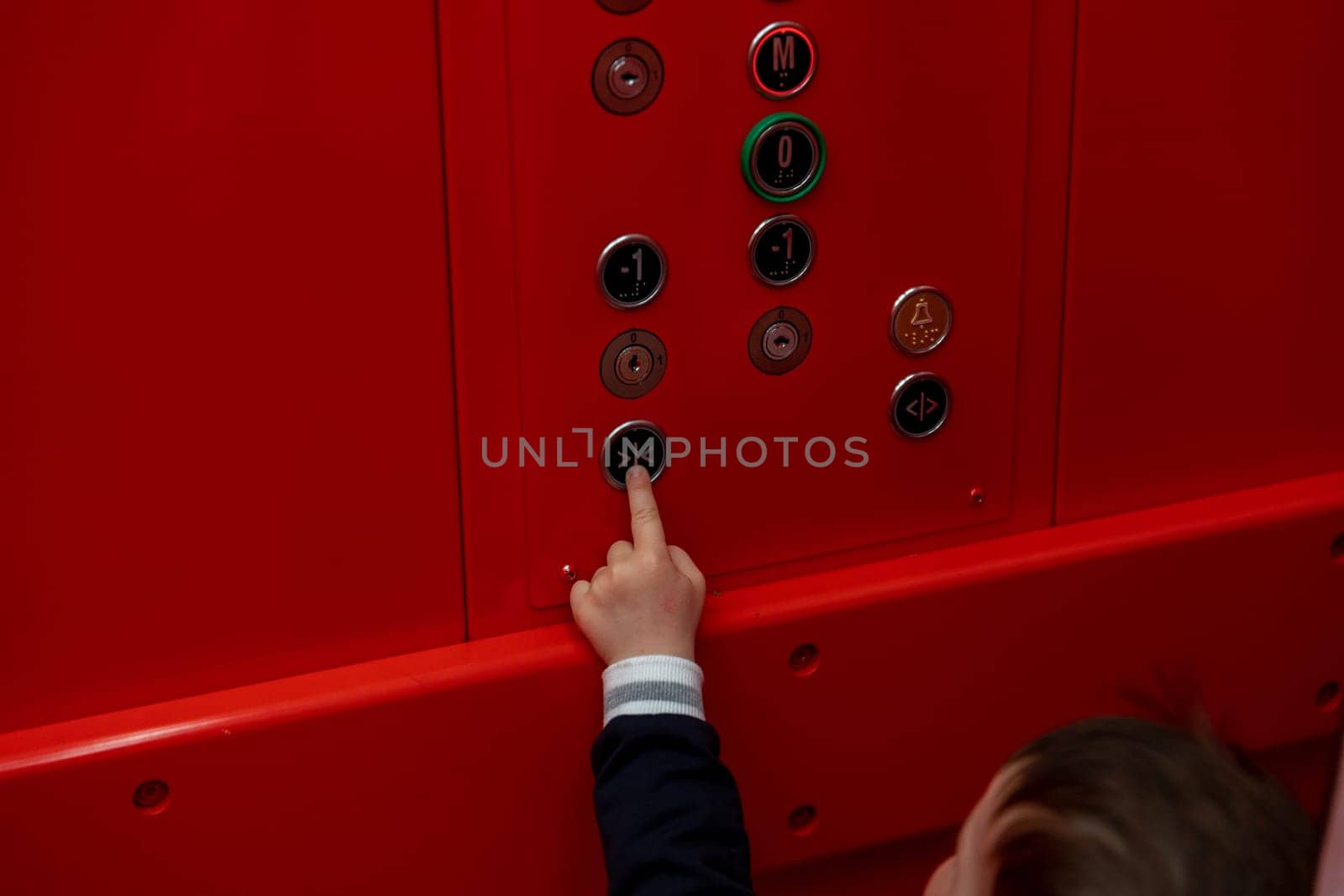 small boy pressing button in red elevator. High quality photo