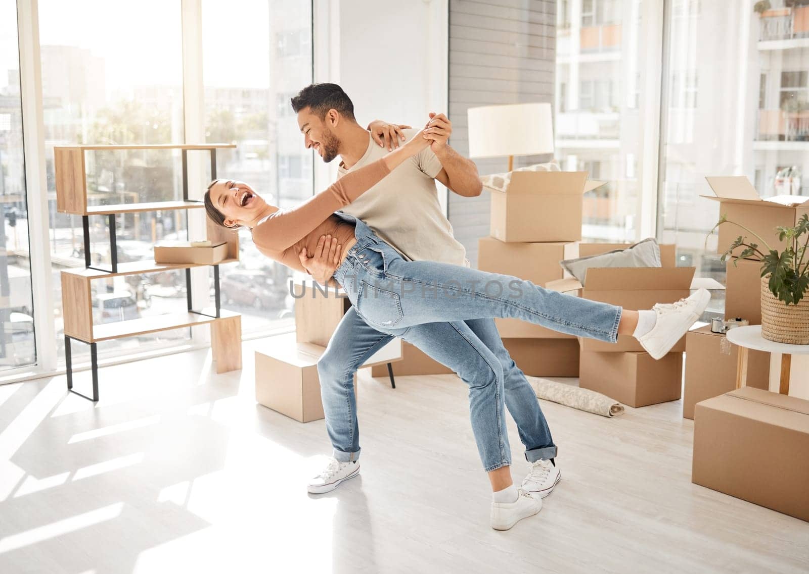 Celebration, dance and couple with boxes, property and excited with rent apartment, mortgage and home. Cardboard, man and woman dancing, real estate and moving with love, quality time and romance by YuriArcurs