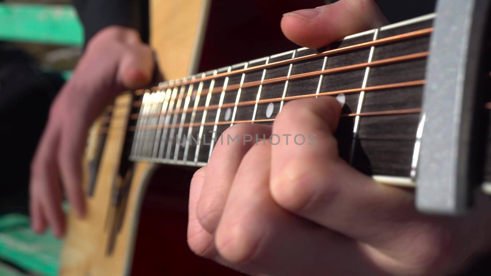 A young man plays the guitar in the park. The hand of a man closeup. 4k