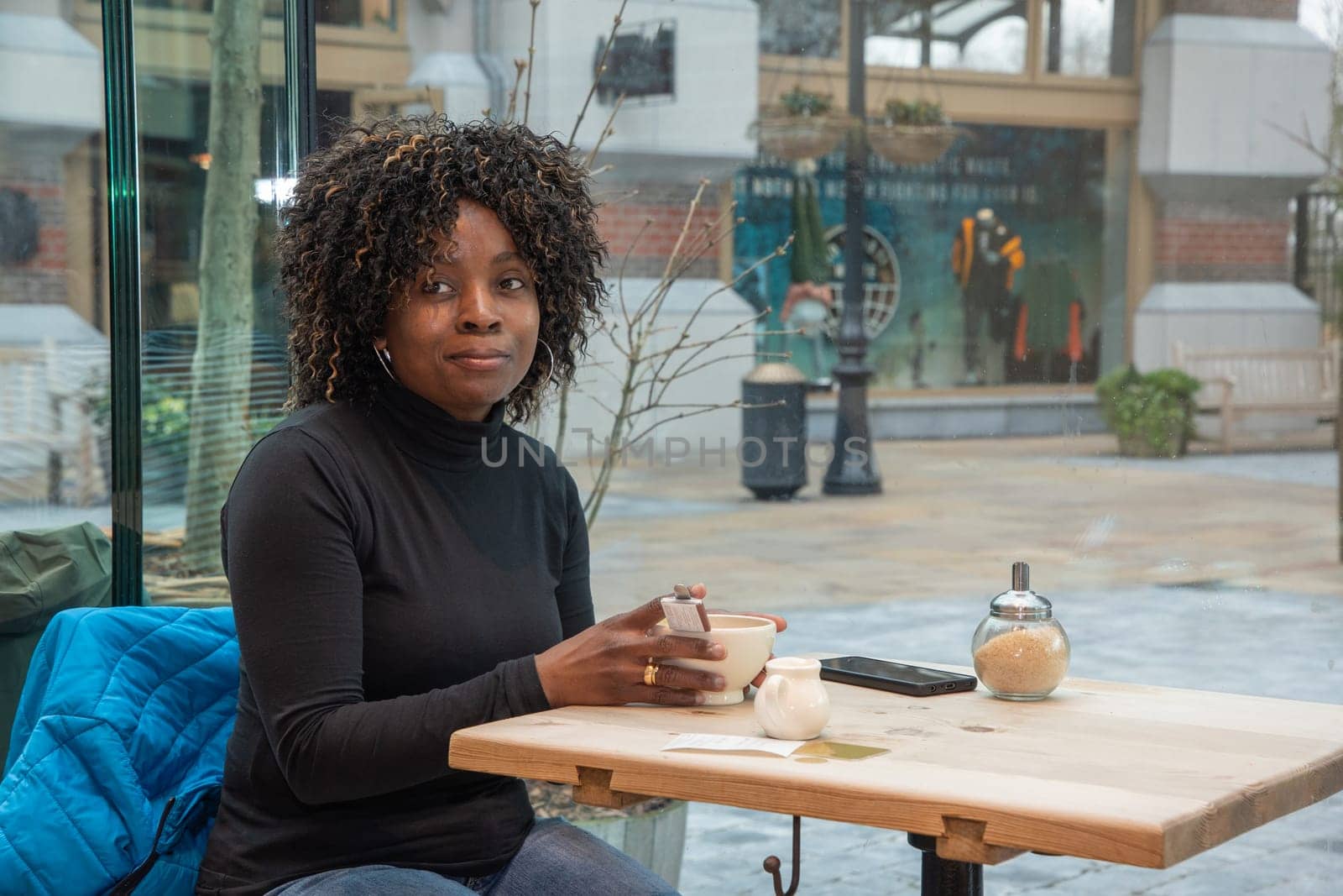 African young woman without makeup sits in a cafe in the morning, having just woken up, and drinks coffee, High quality photo