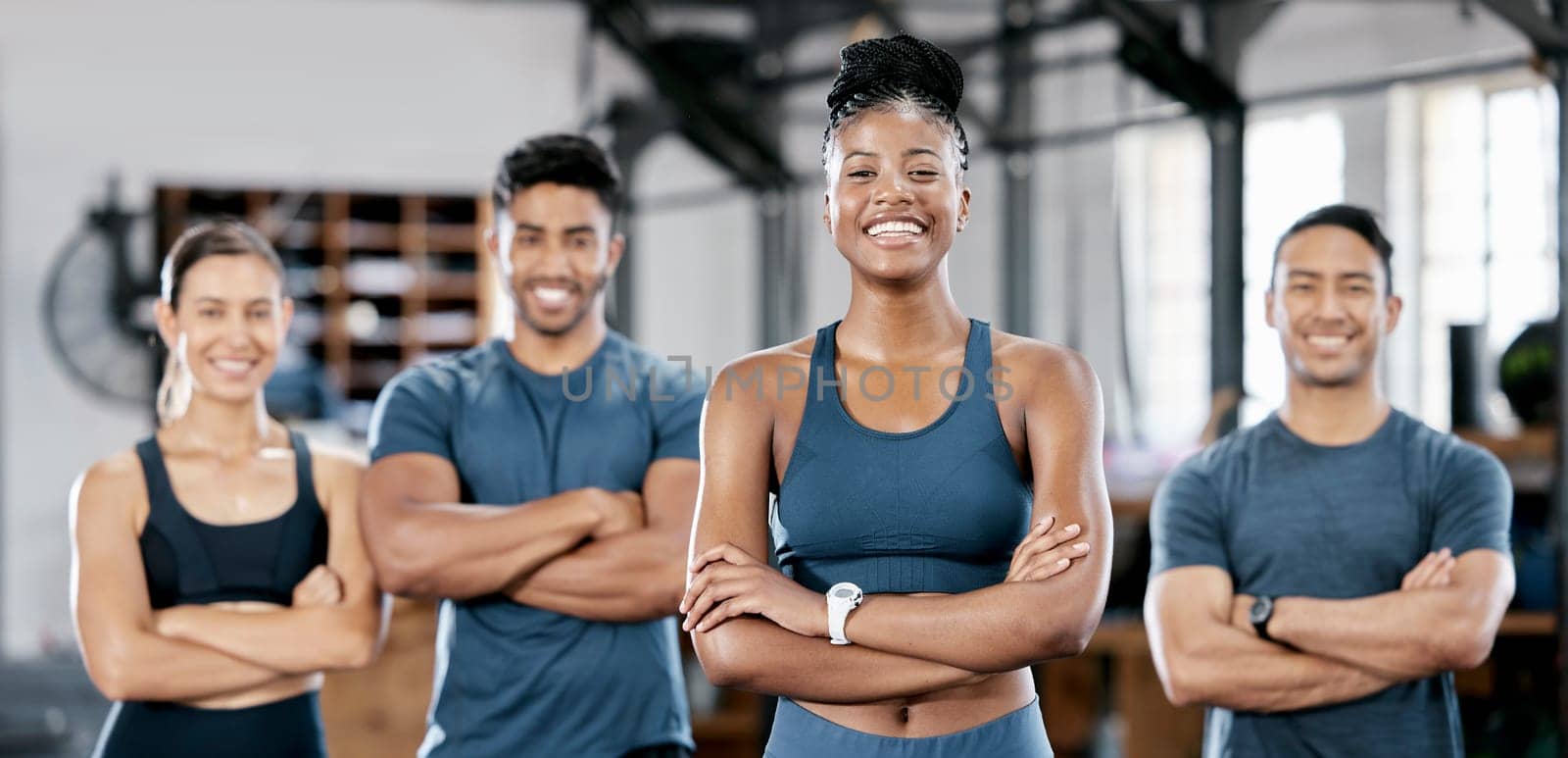 Fitness, portrait and woman personal trainer with a team standing with crossed arms in the gym. Sports, collaboration and happy people after exercise, workout or training class in sport studio. by YuriArcurs