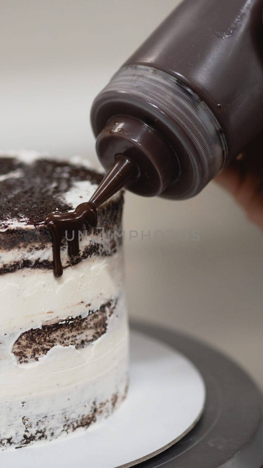 pastry chef preparing a chocolate frosted dripped icing cup cake with sweet fruit topping and golden brush strokes