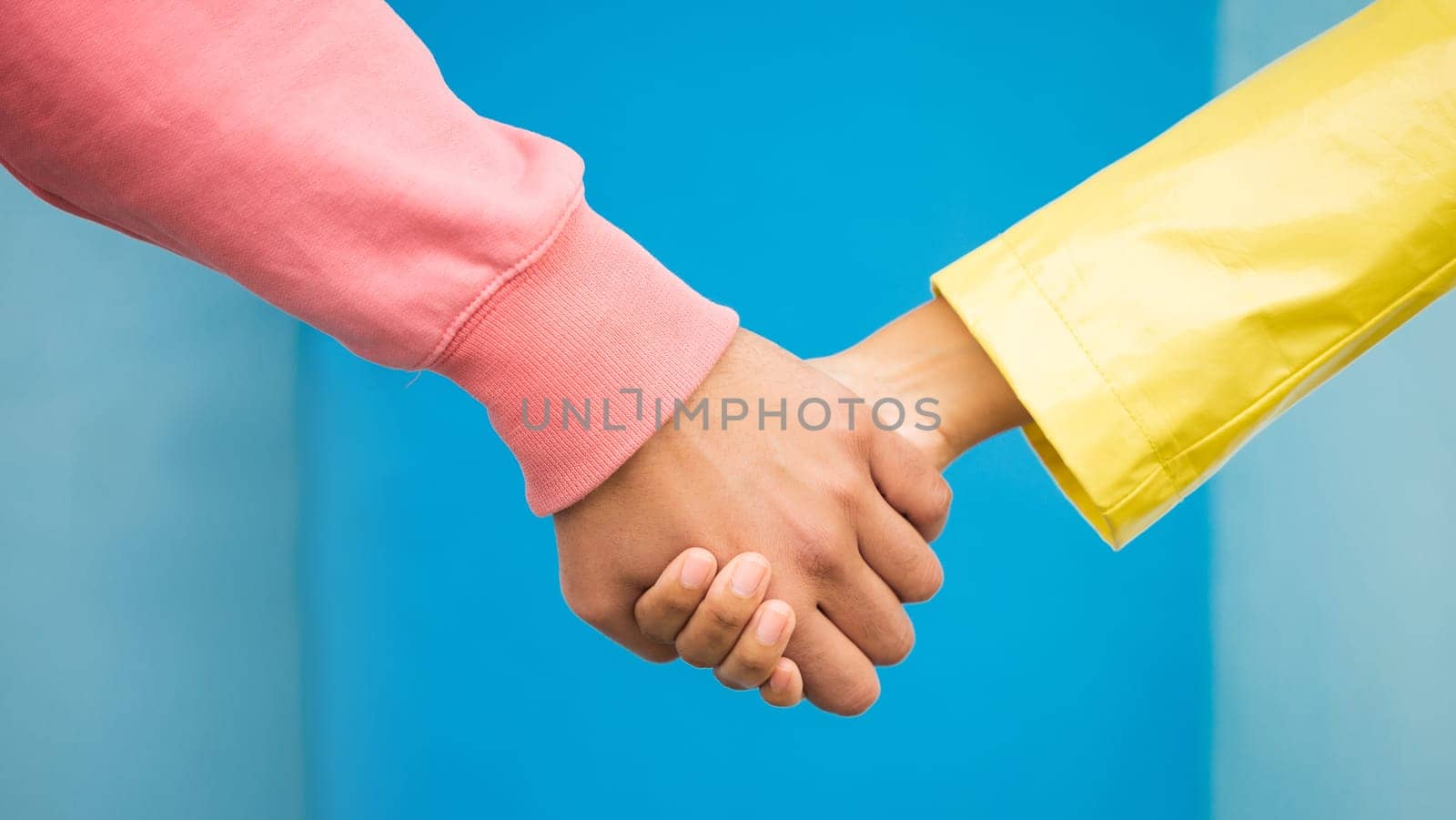 Couple, love and holding hands together for support care, relationship and bonding in blue background studio. Man, woman and hand for partnership, romance trust and solidarity or compassion lifestyle.