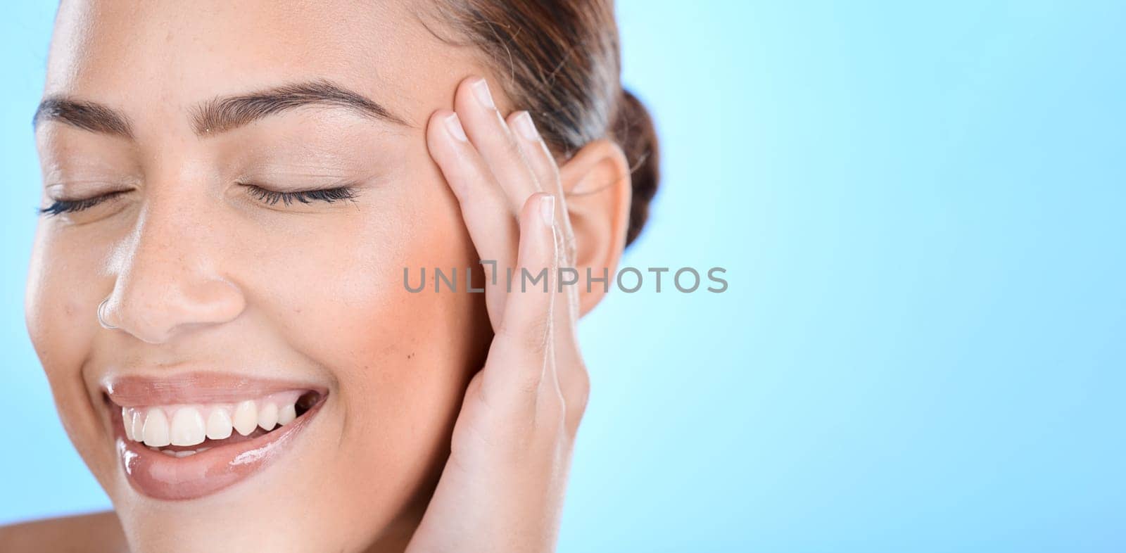 Woman, skincare and hands on face in studio for makeup, wellness or gentle cleaning on blue background. Face, beauty and girl skin model relax in luxury, facial and cosmetic treatment while isolated.