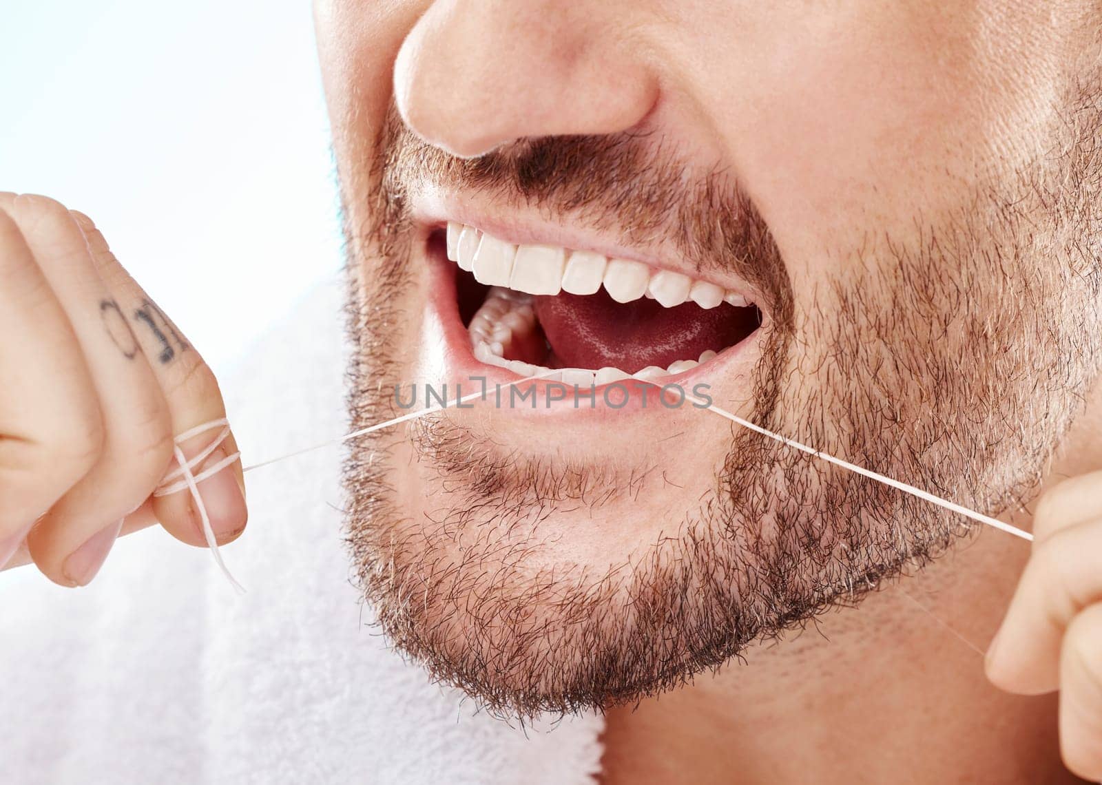 Dental, hygiene and man flossing his teeth in a studio for oral care, grooming or health. Wellness, healthy and closeup of male model doing fresh, clean and natural mouth routine by white background. by YuriArcurs