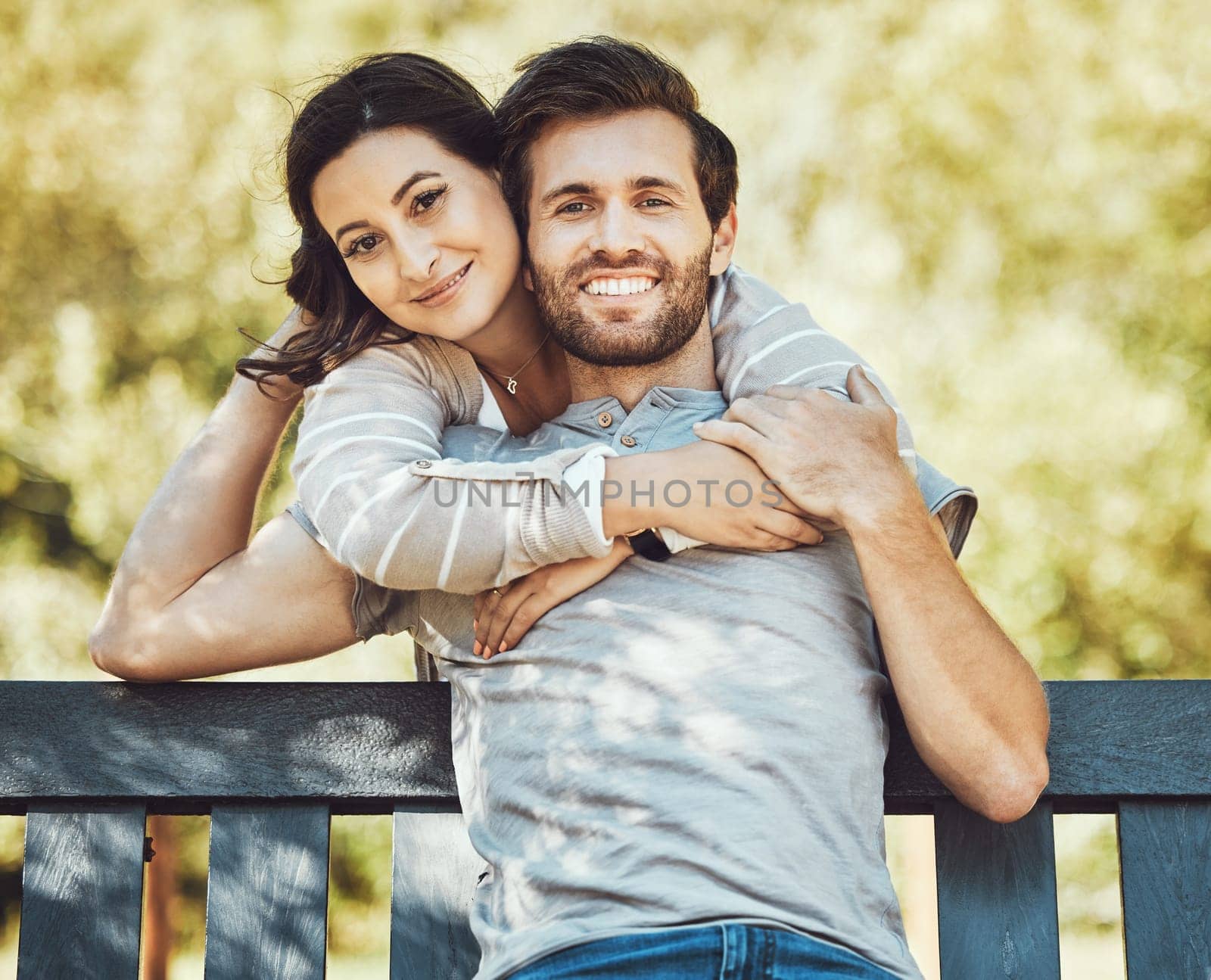 Love, couple and hug on park bench, portrait and having fun time together outdoors. Valentines day, romance relax and care of man and woman hugging, embrace and cuddle on romantic date and smile