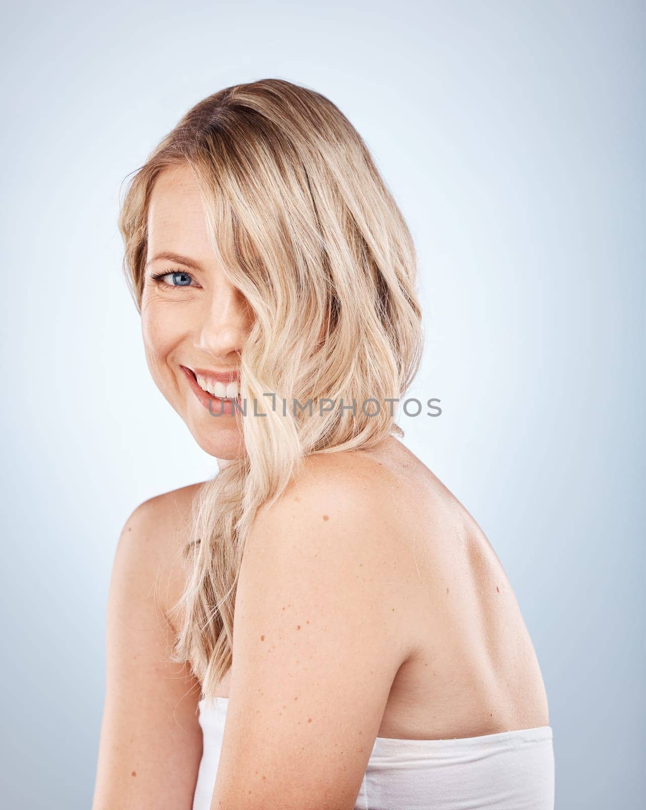 Hair, portrait and blonde woman with smile for haircare, styling and treatment on a white background. Hairstyle, waves and blond female with stylish glamour for healthy texture in a salon studio.