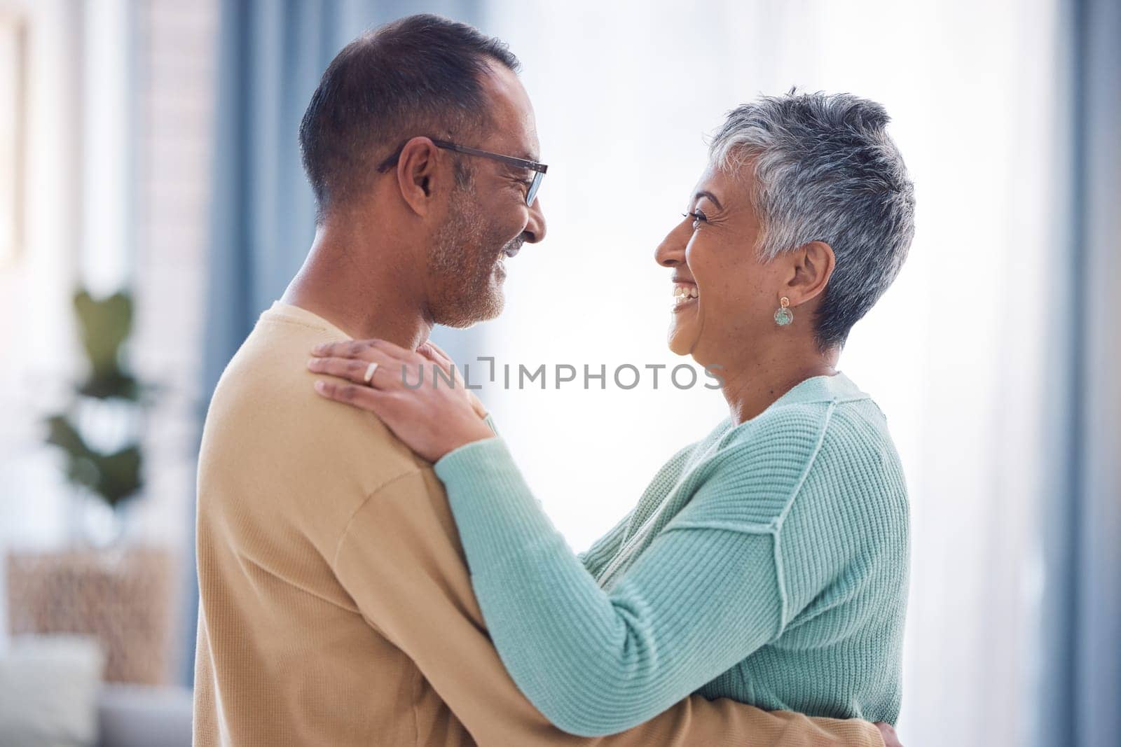 Happy, love and romance with a senior couple laughing, hugging or dancing together in their home. Dance, romantic and smile with a happy mature man and woman enjoying their retirement while bonding by YuriArcurs