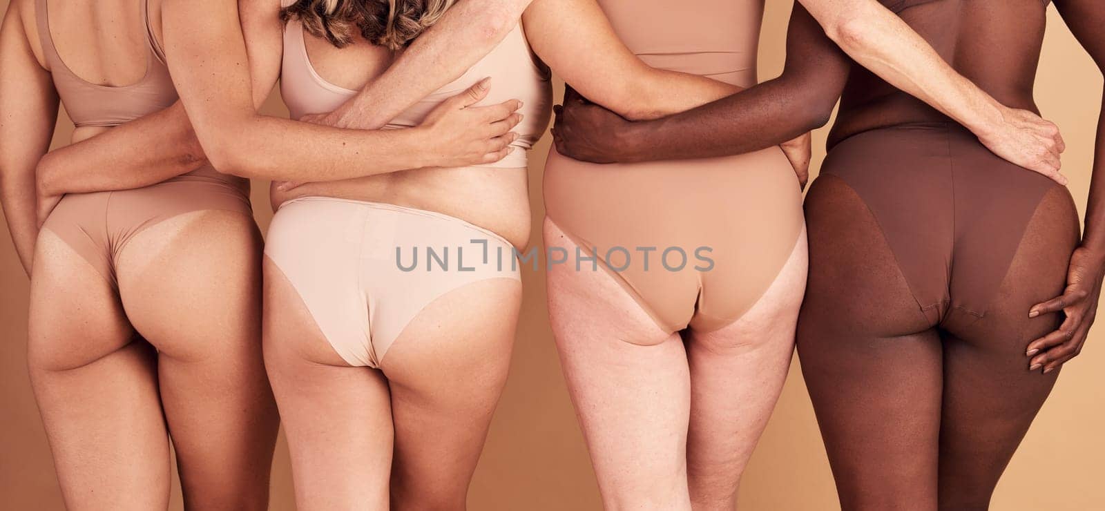 Self love, diversity and women underwear group for skin color inclusivity panties campaign back view. Body positive, plus size and interracial people hug together on beige studio background