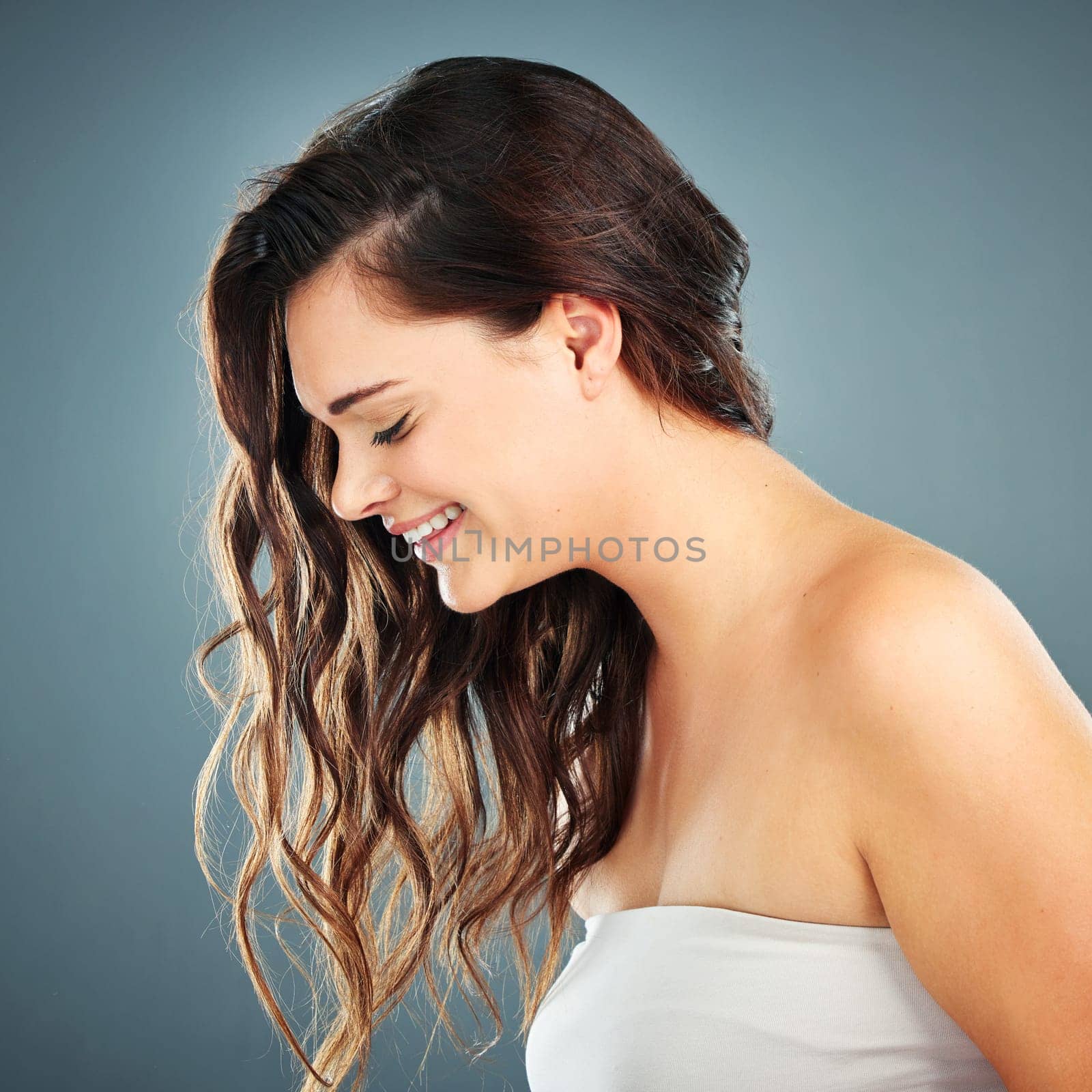 Hair, woman and brunette with wavy or curly hair for beauty and cosmetology on a grey studio background. Cosmetics, haircare and hairstyle of a beautiful female with hair care and healthy hair by YuriArcurs