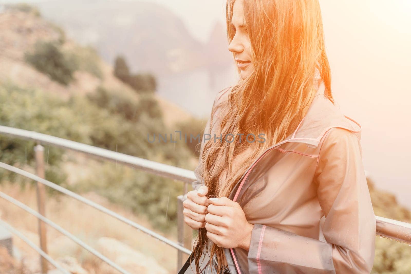 Woman rain umbrella. Happy woman portrait wearing a raincoat with transparent umbrella outdoors on rainy day in park near sea. Girl on the nature on rainy overcast day. by panophotograph