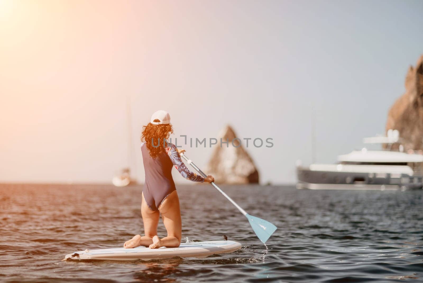 Woman sup yoga. Middle age sporty woman practising yoga pilates on paddle sup surfboard. Female stretching doing workout on sea water. Modern individual hipster outdoor summer sport activity