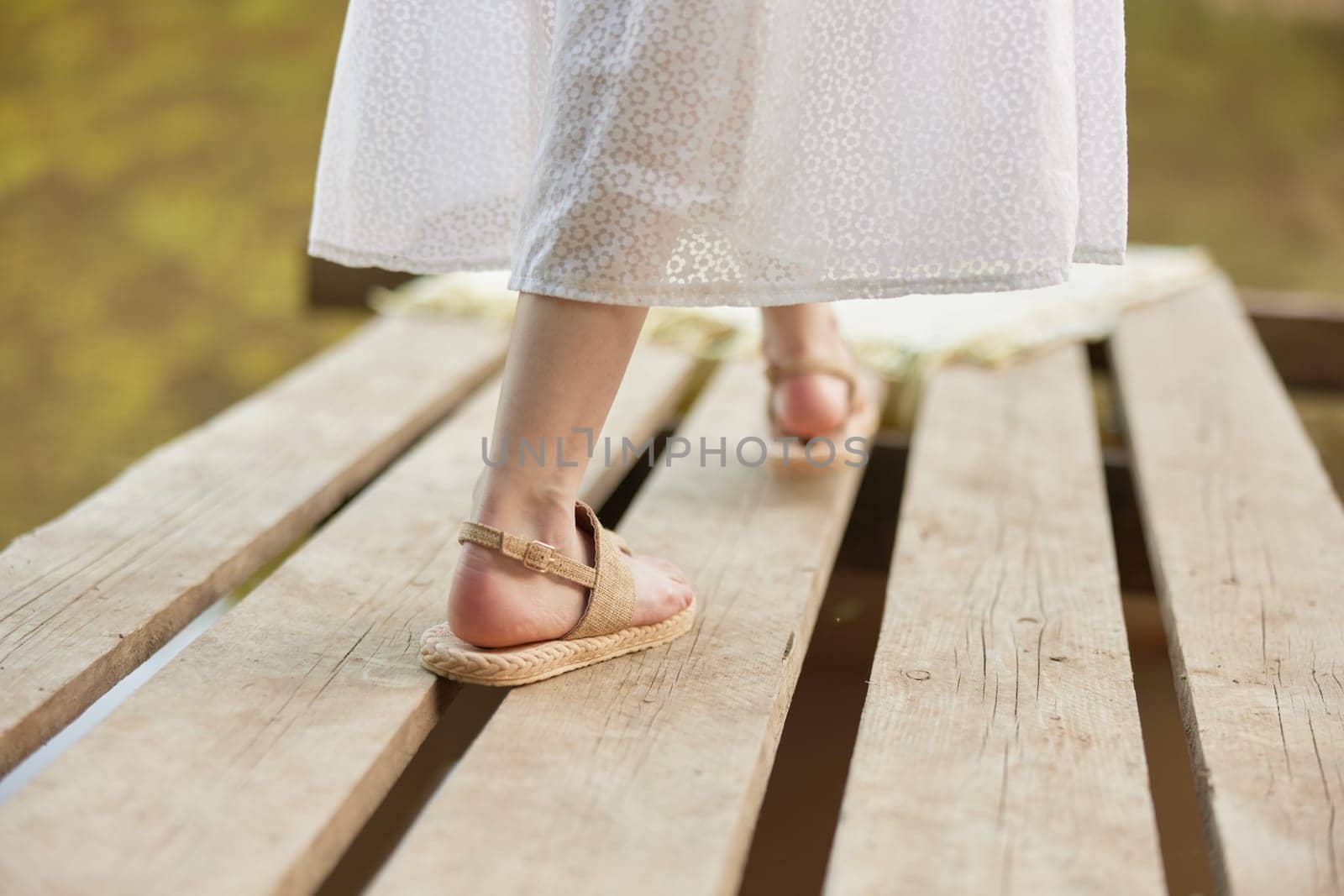 girl's legs in summer sandals on the pier in summer. High quality photo