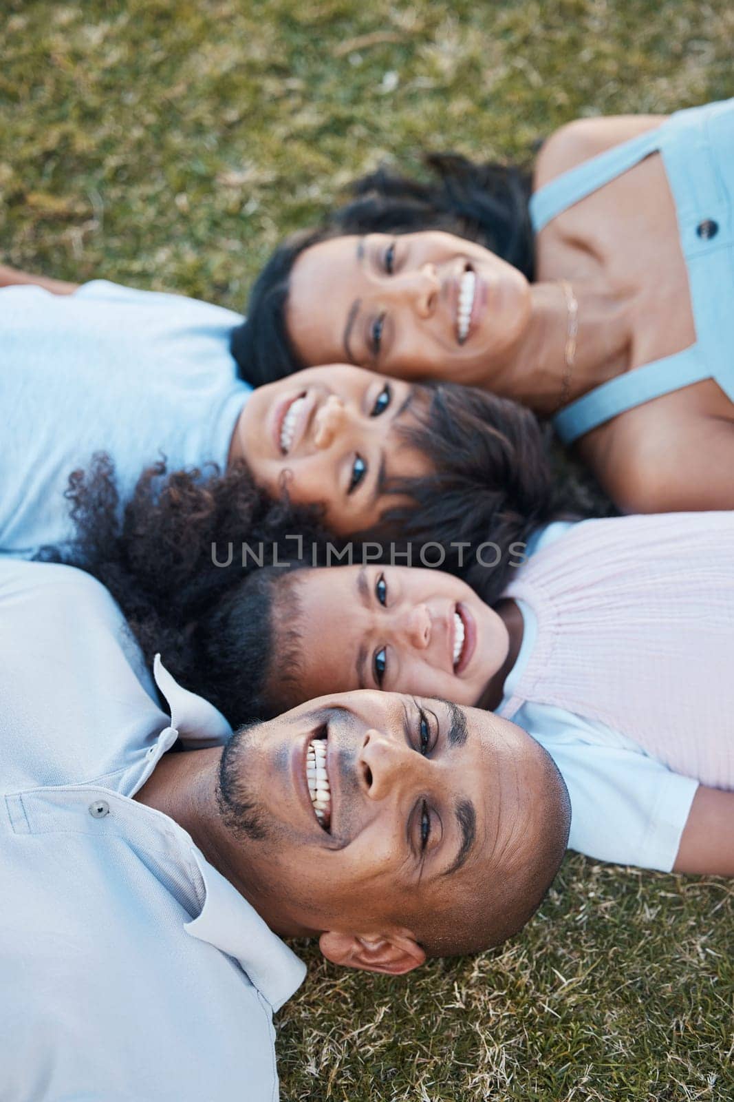 Family, happy portrait and lying on grass in garden with mother, father and kids together with love. Face, top view and dad with mom and children with parent support and care on a lawn with smile.