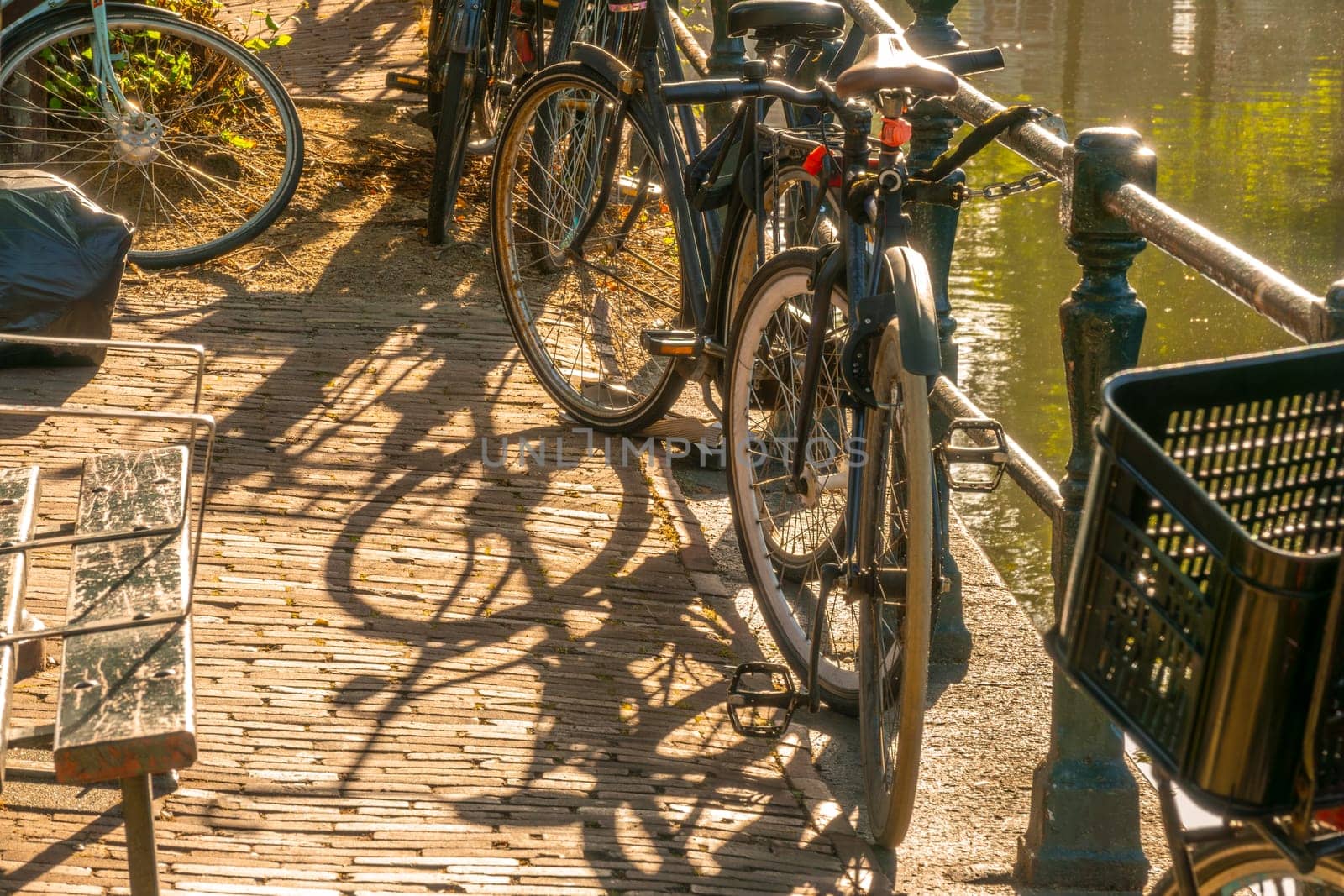 Netherlands. Sunny morning on the Amsterdam Canal Quay. Bicycles by the fence and a bench