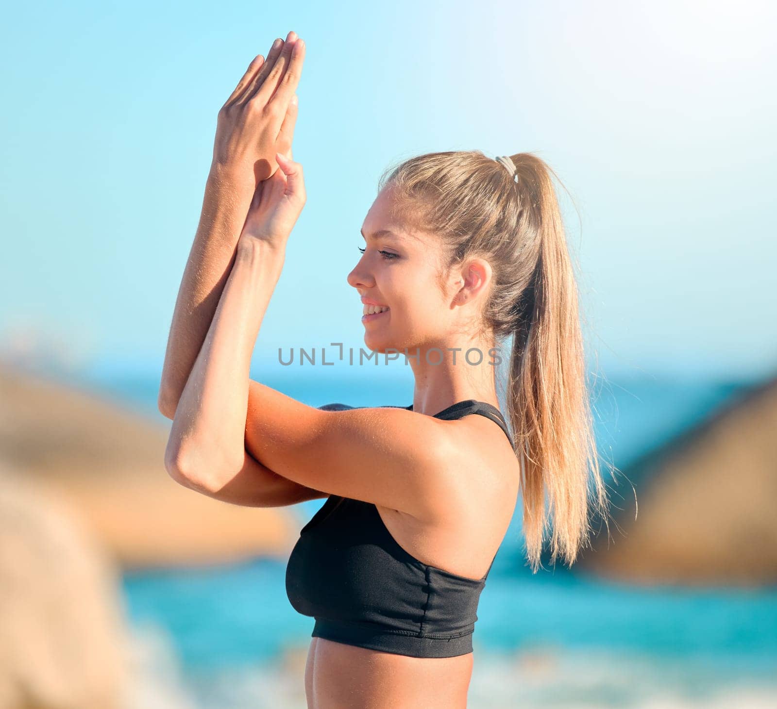 Yoga, meditation and a woman at the beach for zen, wellness or inner peace outdoor in nature. Relax, mindfulness and awareness with a young female yogi meditating against a blue sky for balance.