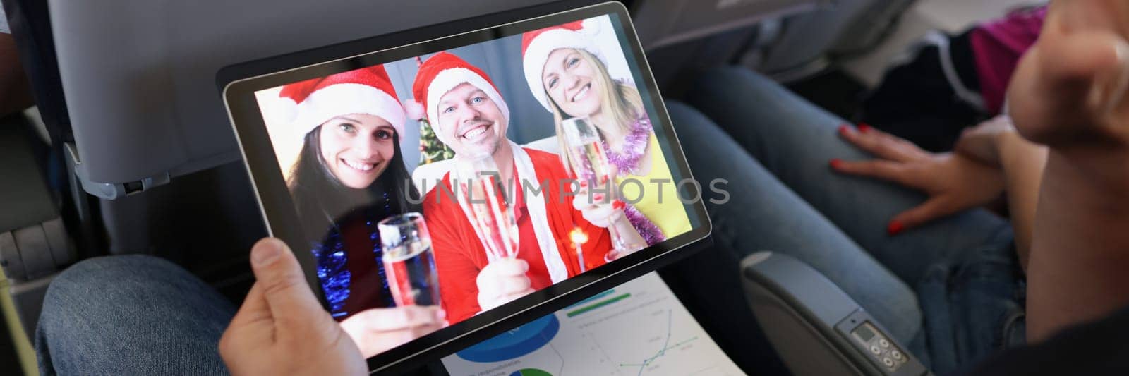 Close-up of man talk on video call with friends, listen to congratulations, festive group of close people celebrate new year. Meet new year on airplane, friendship, technology concept