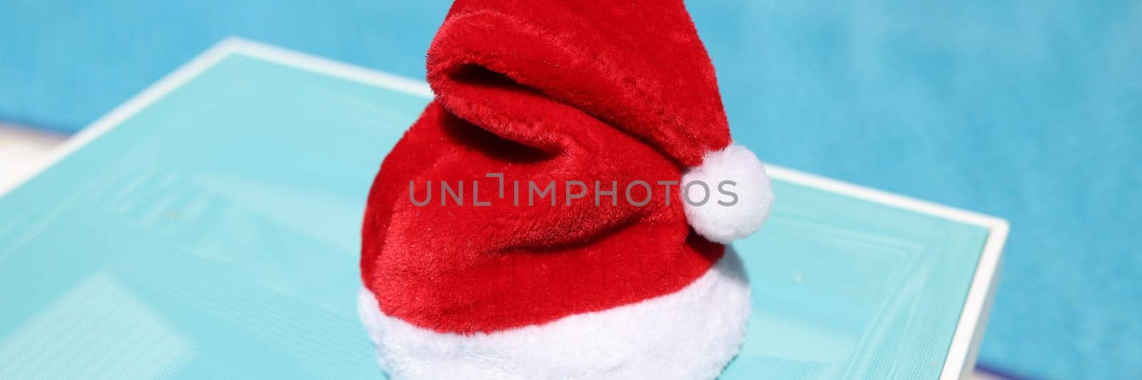 Santa claus red hat standing on beach lounger closeup. Travel to warm countries on new year holidays concept