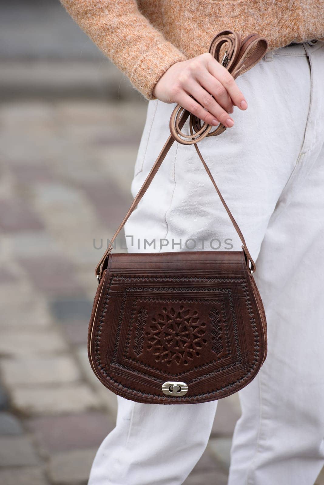 woman in white pants and a beige sweater poses outside with a small leather handbag by Ashtray25