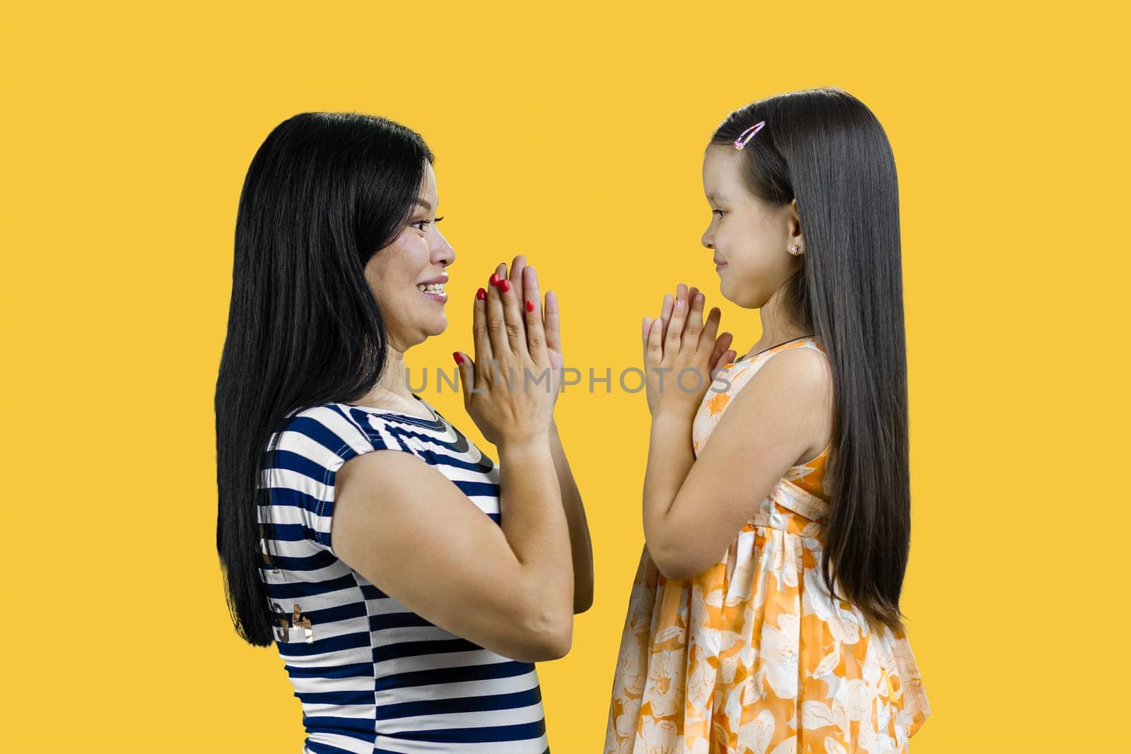 Side view of a young mother and her daughter are playing clapping game cutout. Isolated on yellow. by super_picture