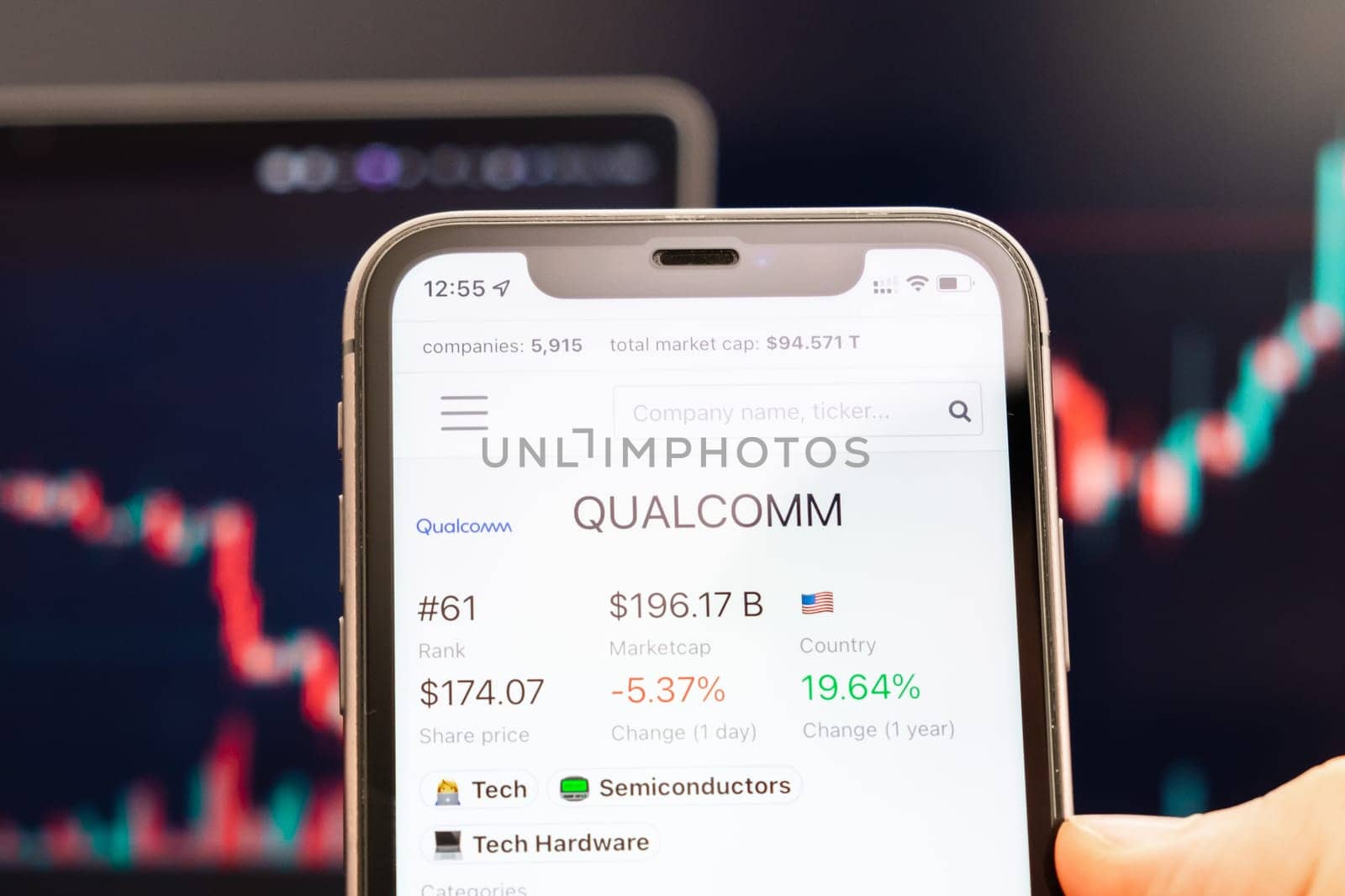 QUALCOMM stock price on the screen of mobile phone in mans hand with changing stock market graphs on the background, February 2022, San Francisco, USA.