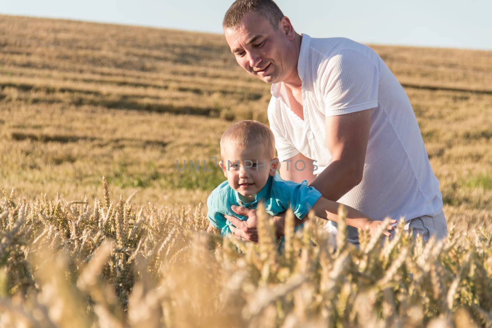 Dad and his little son are having fun walking in a field with ripe wheat. Grain for making bread. the concept of economic crisis and hunger