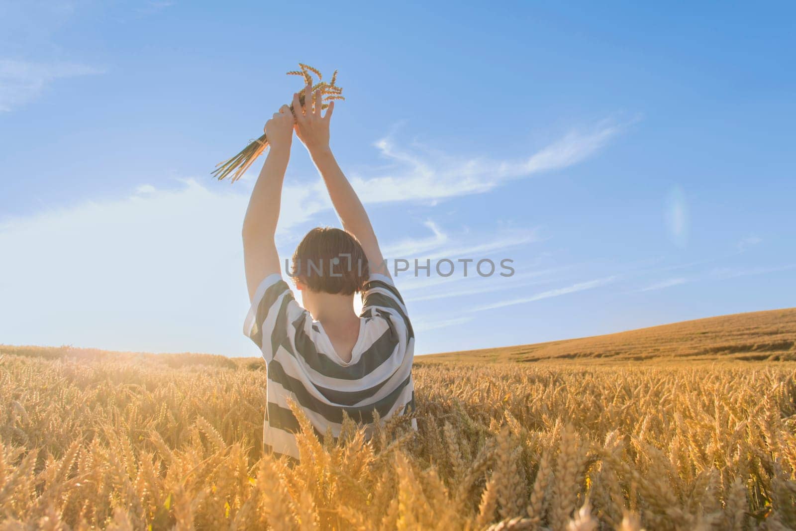 A young guy, a teenager with ears of ripe wheat in a farmer's field. Grain for making bread. the concept of economic crisis and hunger. by Alla_Yurtayeva