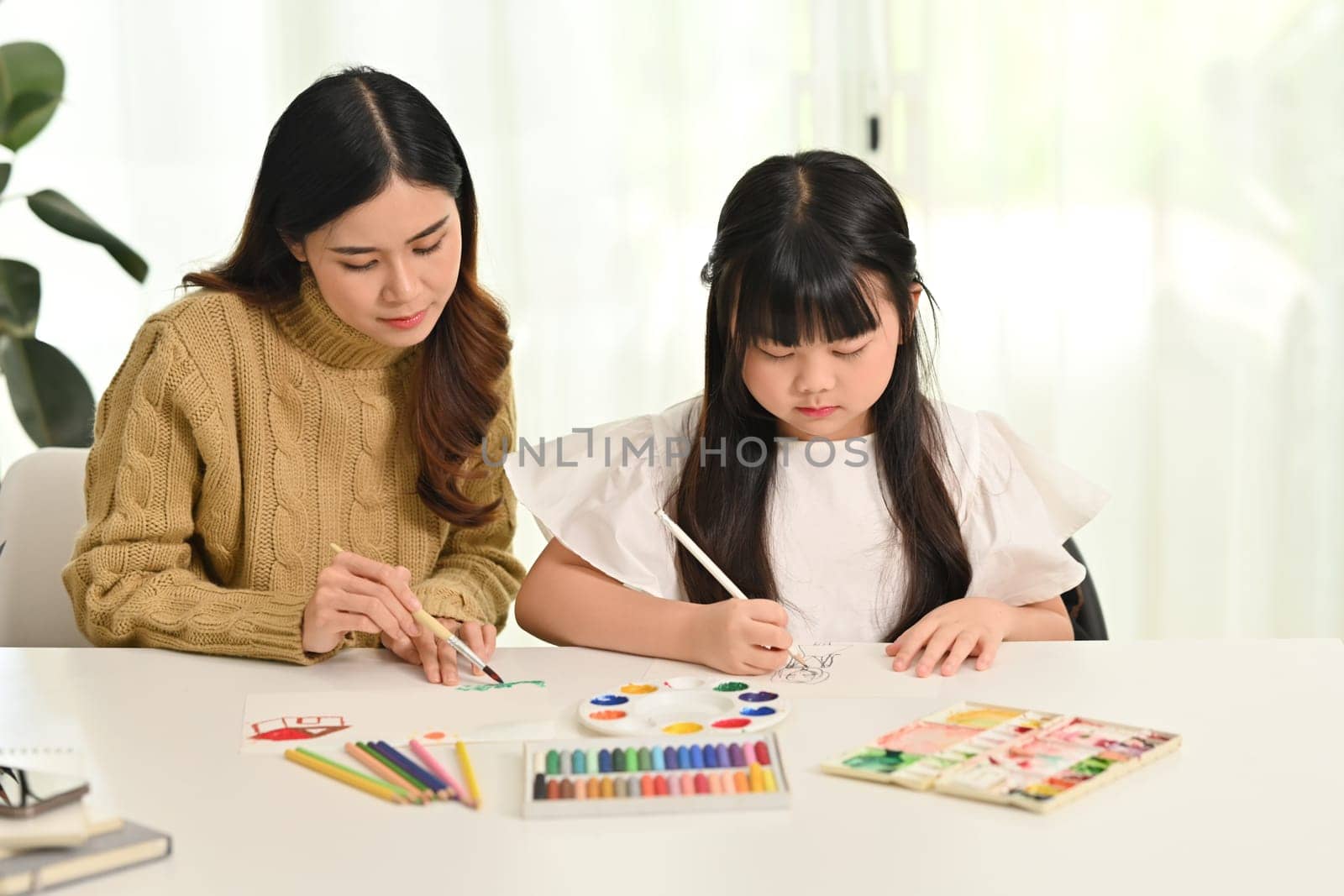 Little asian girl drawing with her mother in living room. Family home leisure concept by prathanchorruangsak