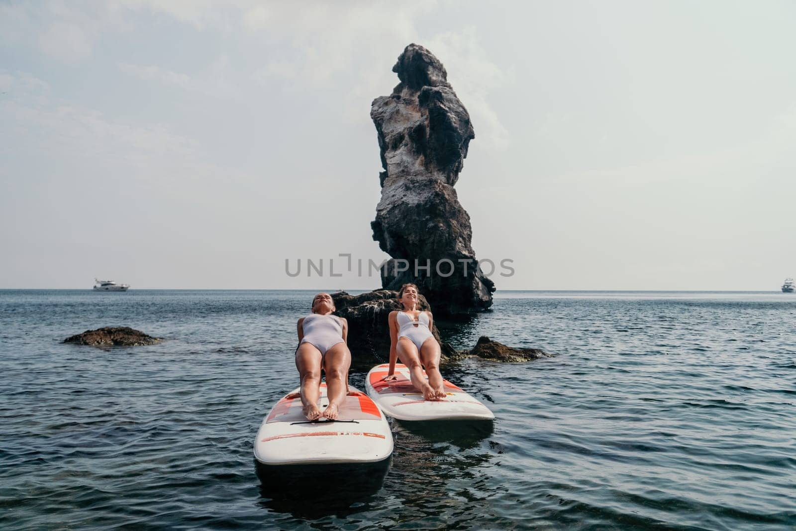 Woman sup yoga. Middle age sporty woman practising yoga pilates on paddle sup surfboard. Female stretching doing workout on sea water. Modern individual hipster outdoor summer sport activity