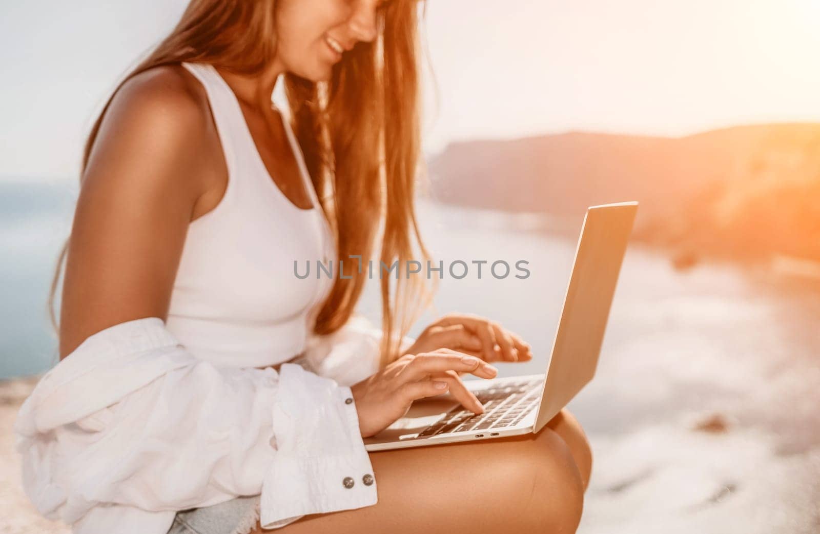 Woman sea laptop. Business woman in yellow hat freelancer with laptop working over blue sea beach. Girl relieves stress from work. Freelance, digital nomad, travel and holidays concept by panophotograph