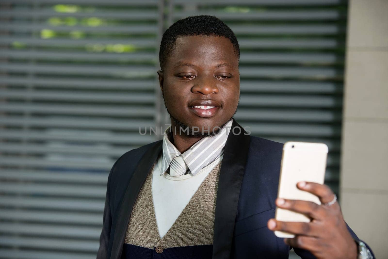 young man standing in a suit looking at cell phone while smiling.