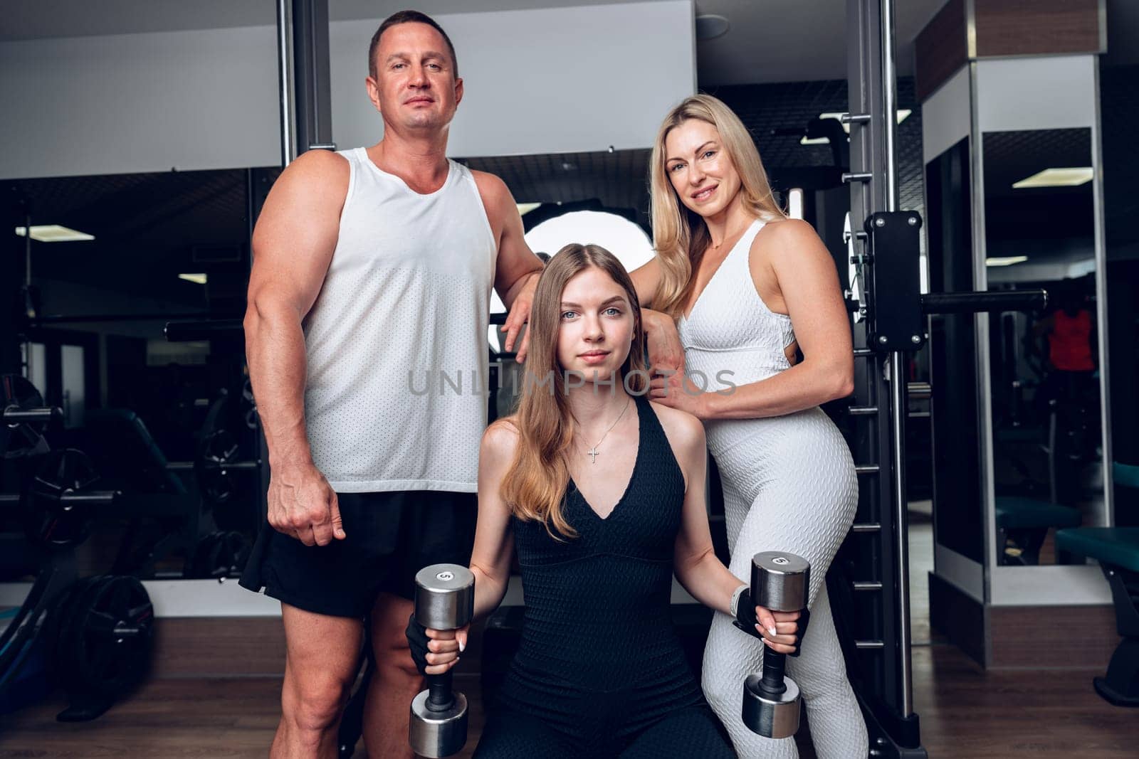 Mother, father and teen daughter training together in a gym by Fabrikasimf