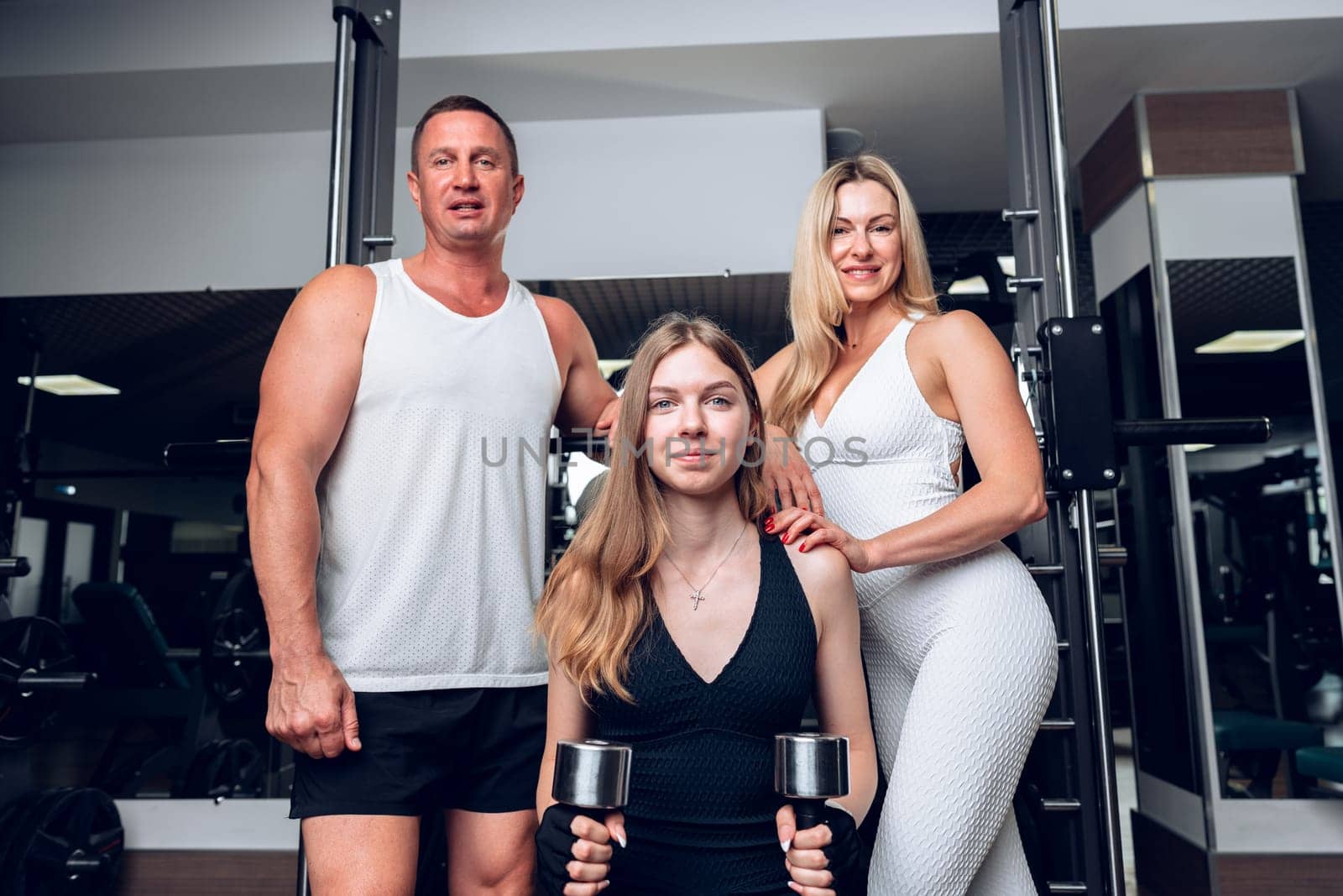 Mother, father and teen daughter training together in a gym, portrait