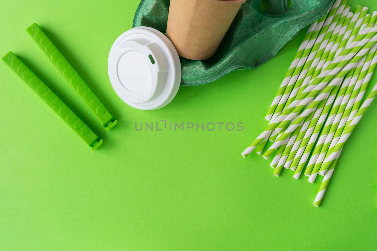 Plastic and recycling concept, closeup top view. Green background with glass, tubes, bag clip, stand, lid