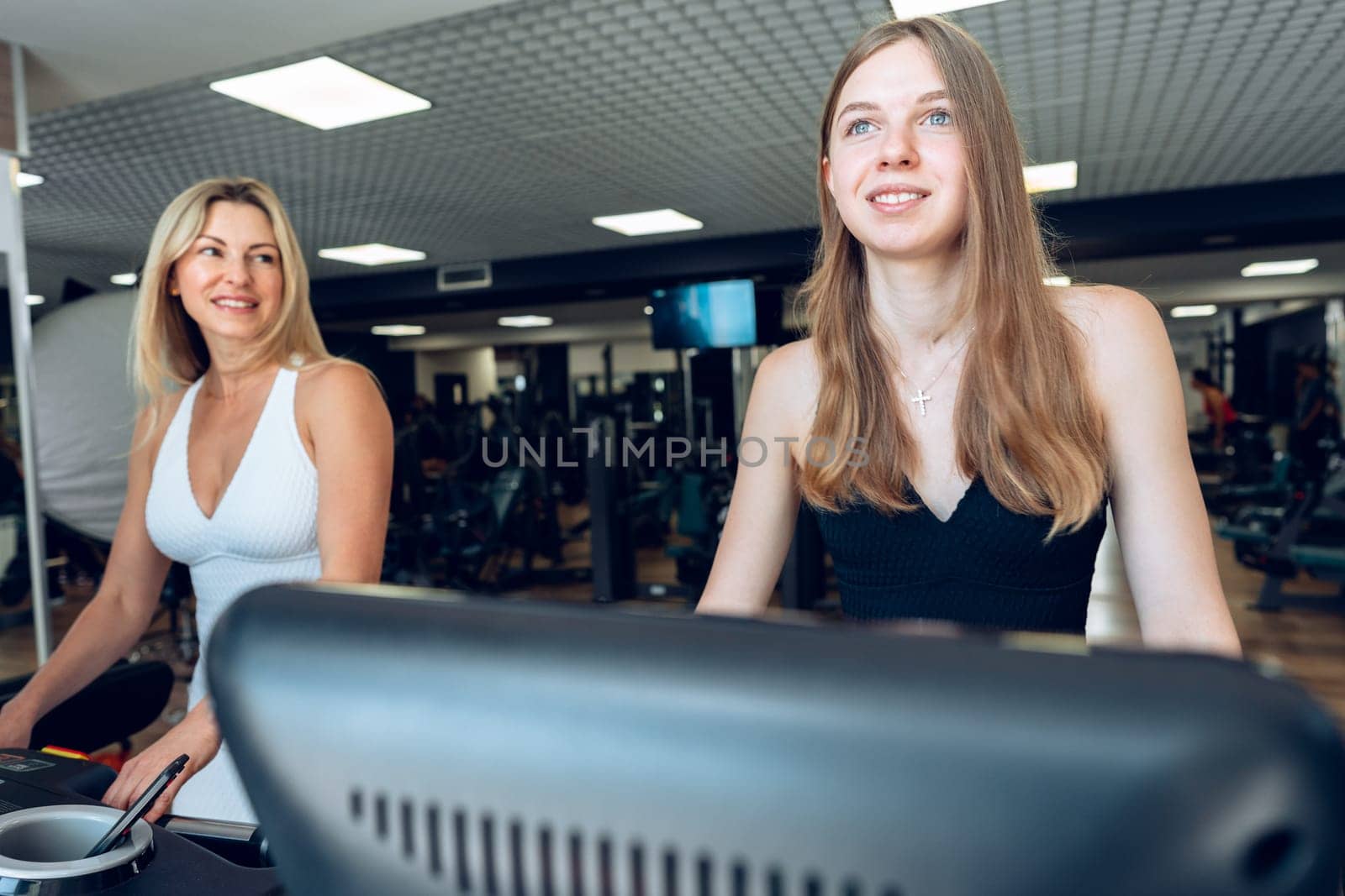 Mother and teen daughter in sportswear exercise on treadmill at the gym together
