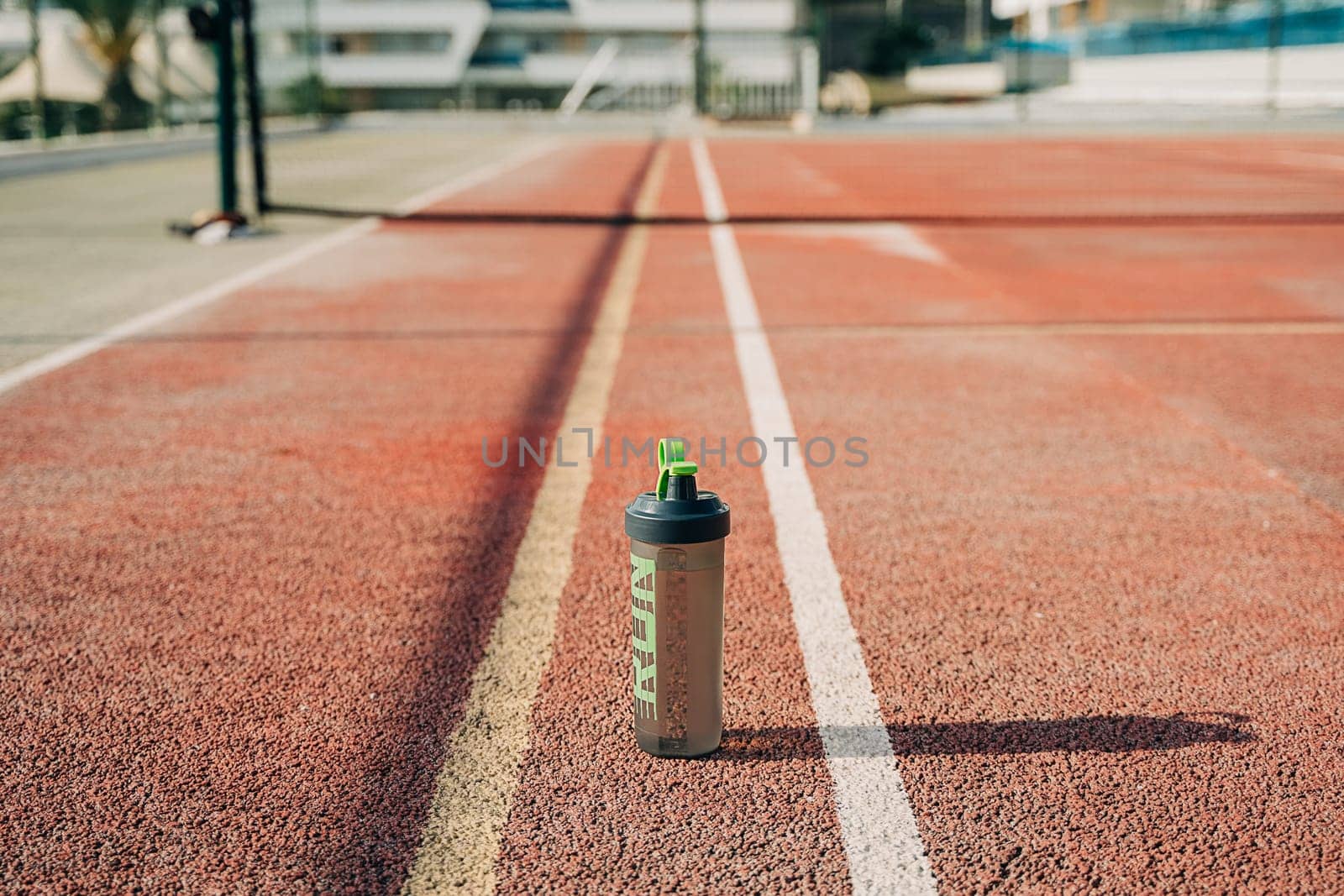 Close up of water blender bottle standing on tennis court. No people, copy space
