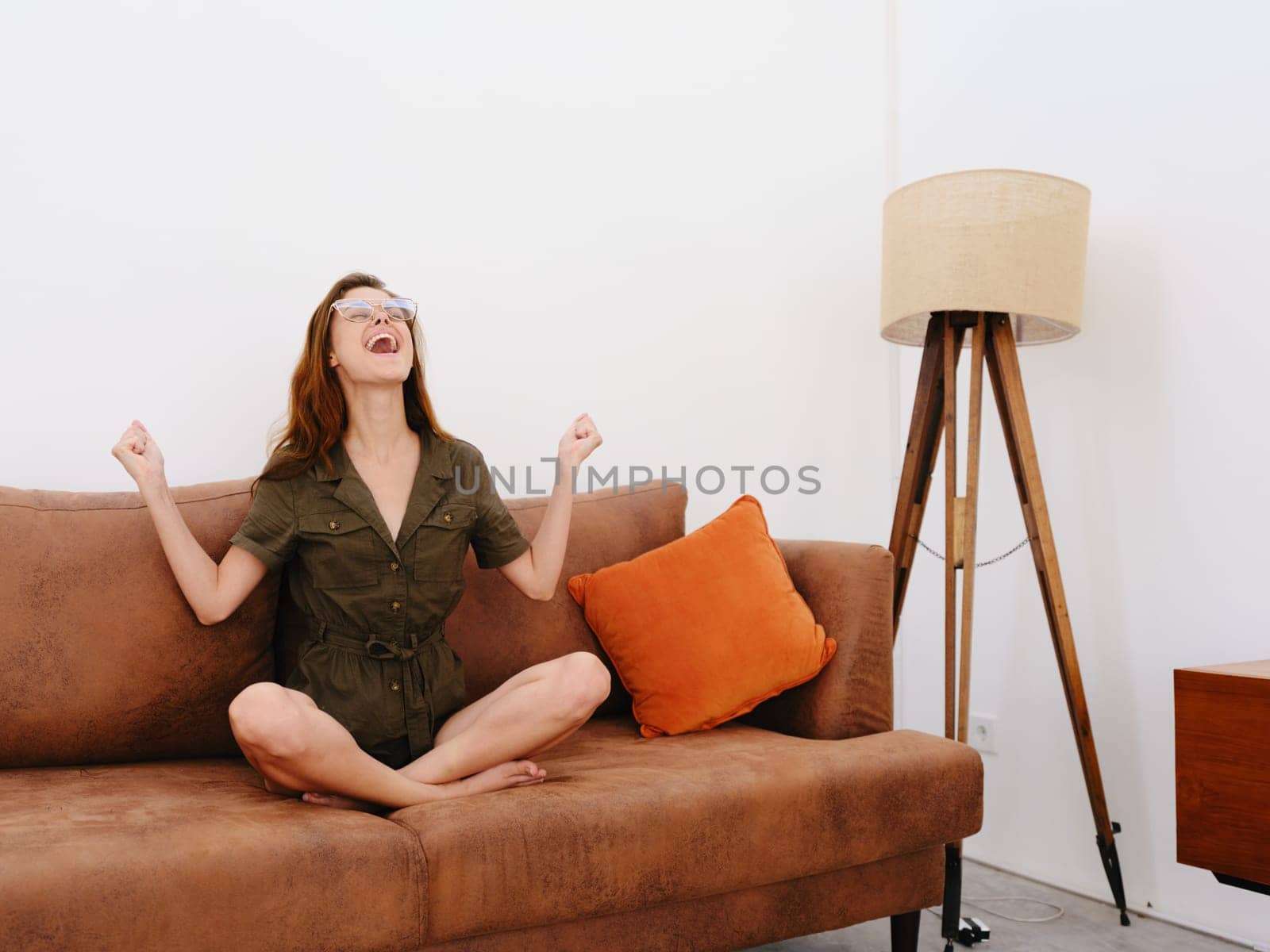 Woman model sitting on the couch at home smile, surprise, joy and relaxation, modern interior lifestyle, copy space, fall color palette. by SHOTPRIME