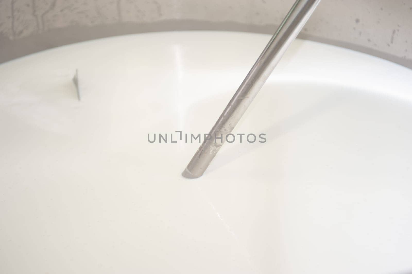 Cheesemaker cooking stirring italian bufalo organic milk in stainless steel caudrons, to produce ricotta cheese, italian food excellence worldwide export.