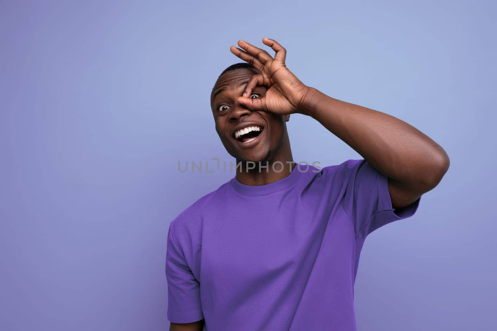 young positive friendly african guy with a short haircut dressed in a basic t-shirt against the background with copy space.